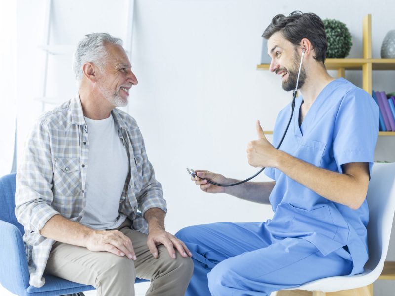 young-doctor-gesturing-thumb-up-elderly-patient